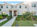 Charming front view of modern townhome, featuring manicured landscaping, a brick-accented porch, and ample sunlight at 2569 Reading Trl, Kissimmee, FL 34746