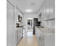 Galley kitchen features modern appliances, stone countertops, and bright white cabinetry at 30 Las Palmas Way, Kissimmee, FL 34743