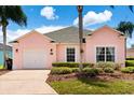 Lovely pink single-story home with lush landscaping, a green lawn, and a well-maintained front yard at 407 Reserve Dr, Davenport, FL 33896