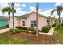 Charming pink home with a green roof, complemented by tropical landscaping and inviting curb appeal at 407 Reserve Dr, Davenport, FL 33896
