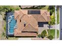 Aerial view of home with tile roof, solar panels, screened-in pool and spa, and manicured landscaping at 478 Chelsea Ave, Davenport, FL 33837