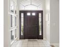 Elegant entryway with a black front door with sidelights, light tile flooring, and wall decor at 1718 Golfview Dr, Kissimmee, FL 34746
