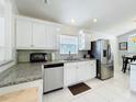 Bright kitchen featuring stainless steel appliances, granite counters, and white cabinets with ample storage at 2105 Mallory Cir, Haines City, FL 33844