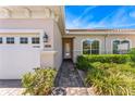 Inviting home entrance with a brick pathway leading to a glass front door, enhanced by beautiful arched windows and garden at 2814 Plymouth Pl, Kissimmee, FL 34741