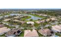 Aerial view of neighborhood homes surrounding a pond, lush greenery, and mature trees under a blue sky at 3010 Winding Trl, Kissimmee, FL 34746