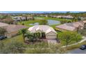 An aerial view of a home with a tile roof, and a well manicured front yard that is surrounded by a pond and lush greenery at 3010 Winding Trl, Kissimmee, FL 34746