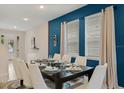 Bright dining room with a large table set for a meal, elegant chairs, and stylish blue accent wall at 385 Southfield St, Kissimmee, FL 34747