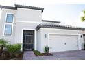 Inviting front of the home with a two-car garage, tile roof, and a screened entry, with fresh landscaping at 3920 Reed Grass Pl, Kissimmee, FL 34746