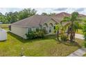 Landscaped home with a large front yard, complemented by palm trees and mature foliage at 502 Woodland Creek Blvd, Kissimmee, FL 34744