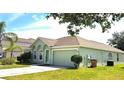 Single Gathering home featuring an attached 2 car garage, green grass, blue skies and mature shade trees at 502 Woodland Creek Blvd, Kissimmee, FL 34744