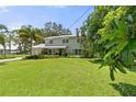 Expansive green lawn with a view of the two-story home featuring a metal roof and lush, tropical landscaping at 6100 Alligator Lake W Shr, St Cloud, FL 34771