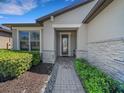 Inviting front porch with stone accents and walkway leading to the decorative glass front door at 688 Cordoba Dr, Davenport, FL 33837