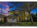 Two-story yellow home with a white garage door, arched entry, and solar panels at 8401 Secret Key Cv, Kissimmee, FL 34747