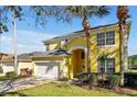 Yellow two-story home featuring a front-entry, white garage door, and well-manicured lawn at 8401 Secret Key Cv, Kissimmee, FL 34747