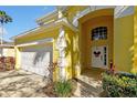 Close up view of the yellow home featuring an arched front entry and white garage door at 8401 Secret Key Cv, Kissimmee, FL 34747