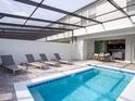 Private pool featuring lounge chairs and a covered area with an outdoor dining set for luxury enjoyment at 8936 Sydney Ave, Kissimmee, FL 34747