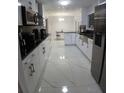 Modern kitchen boasts sleek white cabinets, stainless steel appliances, and elegant marble floors at 2211 New Jersey Rd, Lakeland, FL 33803