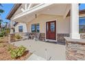 Inviting front porch featuring stone accents, a cozy seating area, and an elegant front door at 3607 Hidden River Ln, Tavares, FL 32778