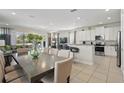Open concept living area with tile floors, dining table, kitchen, and patio access at 785 Desert Mountain Ct, Reunion, FL 34747