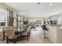 Open concept living area with tile floors, dining table, bar seating, and patio access at 785 Desert Mountain Ct, Reunion, FL 34747