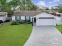 Inviting one-story home featuring a well-kept lawn, colorful landscaping, and a smooth concrete driveway at 7924 Coot St, Orlando, FL 32822