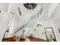 Soaring foyer with a winding staircase, hardwood floors, and statement lighting at 808 Golfpark Dr, Celebration, FL 34747