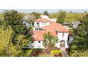 An aerial view of a Mediterranean-style home with a red tile roof surrounded by lush greenery at 8437 Lake Burden Cir, Windermere, FL 34786