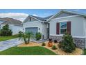 Close up of a single-Gathering home showing its blue garage door, stone accents, and landscaping at 9158 Elsa Ct, Davenport, FL 33897