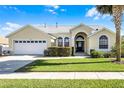 Charming single-story home with a manicured lawn, arched entry, and attached two-car garage at 16014 Hawk Hill St, Clermont, FL 34714