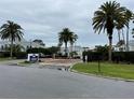 View of the Dockside Condominiums community entrance with a sign and mature palm trees at 2560 Woodgate Blvd # 203, Orlando, FL 32822