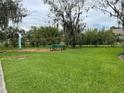Well maintained dog park with green grass, mature trees, picnic bench, and dog waste station at 2560 Woodgate Blvd # 203, Orlando, FL 32822