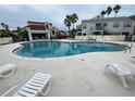 Community swimming pool with lounge chairs and tile patio in front of a building with a red tile roof at 2560 Woodgate Blvd # 203, Orlando, FL 32822