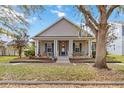 Inviting home featuring a classic front porch, neat landscaping, and a large tree for curb appeal at 3317 Schoolhouse Rd, Harmony, FL 34773