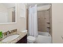 Cozy bathroom with shower-tub combo, granite countertop, and neutral colored tile at 5201 Lake Hinden Cv, St Cloud, FL 34771