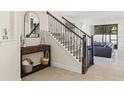 Welcoming foyer featuring decorative staircase, console table, and views into the living space at 5201 Lake Hinden Cv, St Cloud, FL 34771