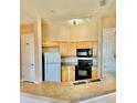 Functional kitchen featuring natural wood cabinets, black appliances, neutral countertops and eat in bar at 619 Terrace Ridge Cir # 619, Davenport, FL 33896