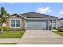 Charming single-story home with a stone accent wall, solar panels, well-manicured lawn, and a two-car garage at 669 Persian Dr, Haines City, FL 33844