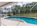 Screened-in pool and spa area with lush landscaping and white picket fence in the background at 7794 Indian Ridge S Trl, Kissimmee, FL 34747