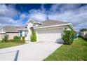 Inviting single-story home featuring a two-car garage, manicured lawn, and colorful flowerbeds at 1061 Citrus Landings Blvd, Davenport, FL 33837