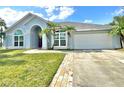 Lovely blue home with a well-kept lawn, palm trees, and a brick-lined driveway at 12450 Greco Dr, Orlando, FL 32824