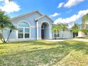 Inviting single-Gathering home featuring a lush green lawn, blue siding and tropical palm trees at 12450 Greco Dr, Orlando, FL 32824