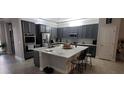 Bright kitchen featuring stainless steel appliances, gray cabinets, a large island, and stylish pendant lighting at 17880 Passionflower Cir, Clermont, FL 34714