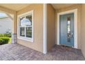 Close-up of a light blue front door and sidelight, with a brick paver porch and a welcoming feel at 2658 Meadowedge Loop, St Cloud, FL 34772