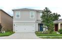 Inviting two-story home with a two-car garage, complemented by a neatly landscaped front yard and a blue front door at 297 Gina Ln, Davenport, FL 33837