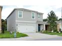 Attractive two-story home with a two-car garage and a blue front door, enhanced by landscaping and a lush green lawn at 297 Gina Ln, Davenport, FL 33837