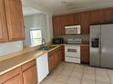 Functional kitchen featuring wood cabinets, white appliances, and a stainless steel refrigerator at 4406 Hidden Meadow Dr, Kissimmee, FL 34746