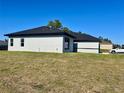 Side view of a single story stucco home with black trim, a dark roof, and a well-maintained lawn at 4491 Sw 151 St, Ocala, FL 34473