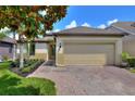 Charming single-story home with a brick driveway, landscaped garden, and attached two-car garage at 514 Cadiz Dr, Davenport, FL 33837