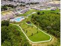 Aerial shot of community amenities including a pool, playground, and a dog park surrounded by lush greenery at 5539 Maddie Dr, Haines City, FL 33844