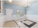 Inviting entryway featuring tile flooring, blue walls, natural light, and stylish chandelier at 784 Seneca Trl, St Cloud, FL 34772